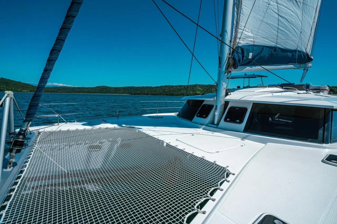 Trampoline on a catamaran over crystal-clear ocean waters.